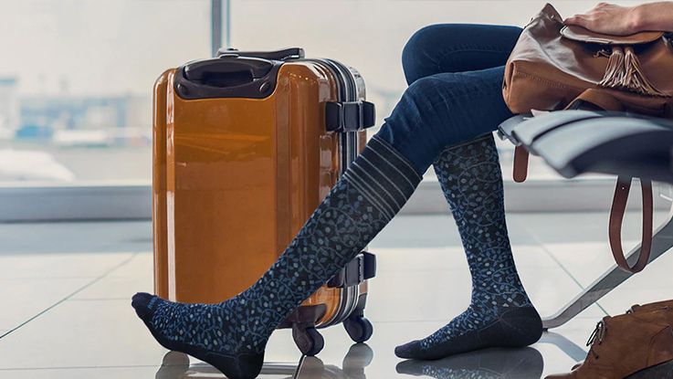 Füße mit grauen Reisestrümpfen während der Reise, zur Unterstützung der Durchblutung und zur Vorbeugung von müden Beinen